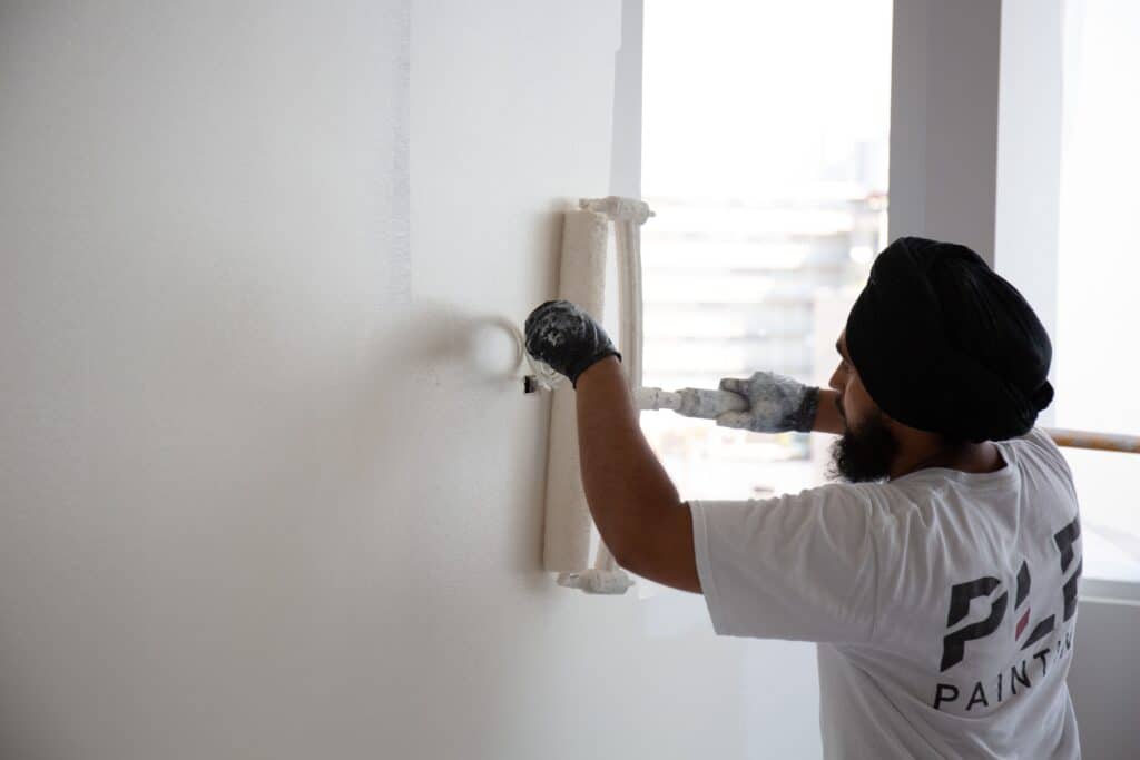 A PLE team member painting with a paint roller
